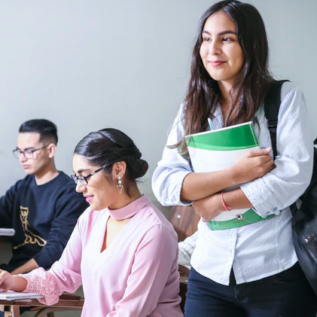 Student standing up in class holding a notebook