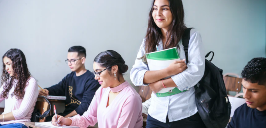 Student standing up in class holding a notebook