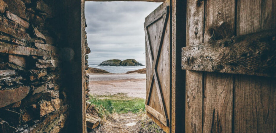 An open wooden door looking out onto a bay