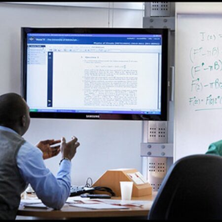 Discussion table set up, a group of people sitting around the table looking over a digital screen