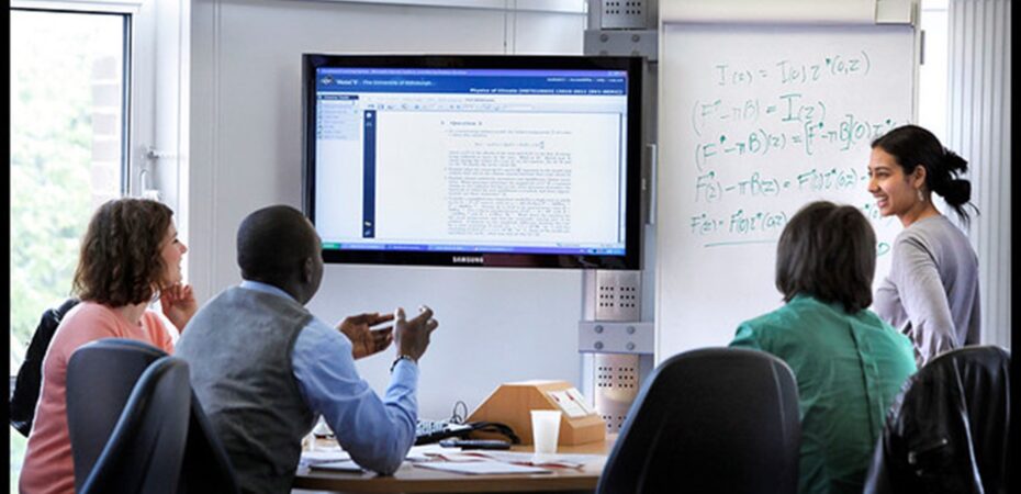 Discussion table set up, a group of people sitting around the table looking over a digital screen