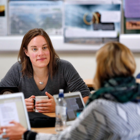 Students and staff at a table engaging in discussion