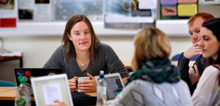 Students and staff at a table engaging in discussion