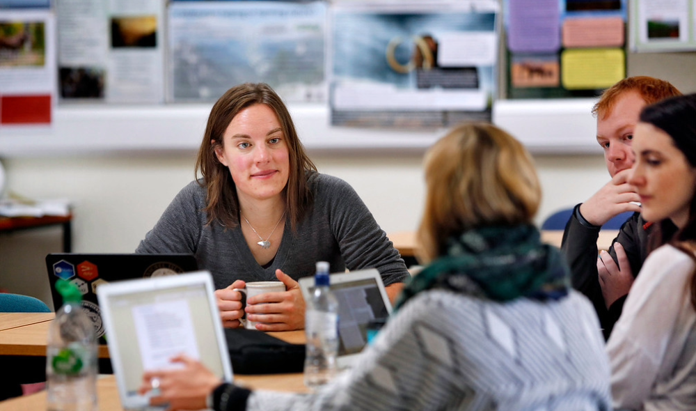 Students and staff at a table engaging in discussion