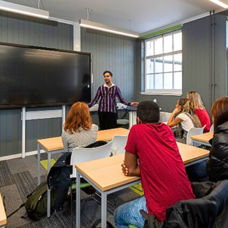 Photograph of students in a lecture hall and teacher giving a talk