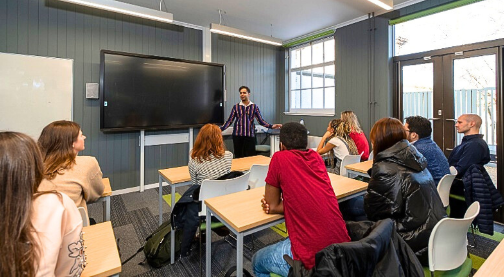 Photograph of students in a lecture hall and teacher giving a talk