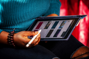 A photograph of a person holding an electronic tablet