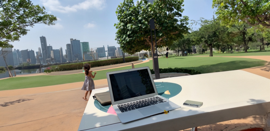 Laptop on a table and a child playing in a park at the background