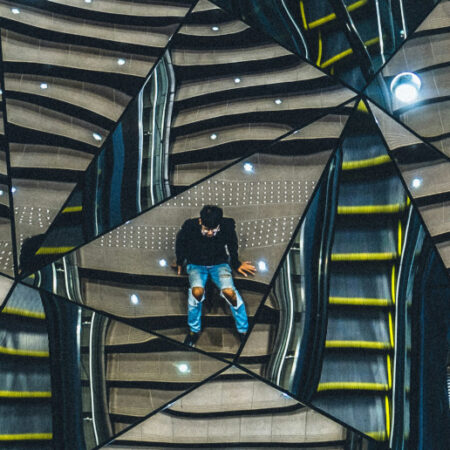 Man sitting on stairs reflected multiple times