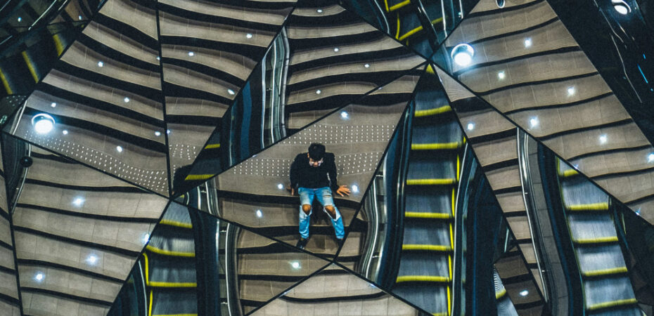 Man sitting on stairs reflected multiple times