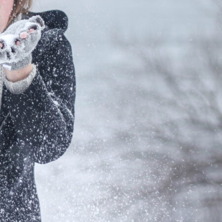 Photo of lady blowing snow out of her hands with snowy backdrop