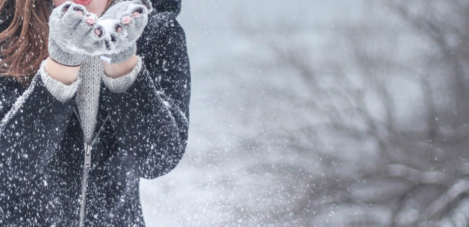 Photo of lady blowing snow out of her hands with snowy backdrop