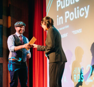 Photo of Henry Myers accepting the award on Hannah's behalf from Dora (EUSA President).