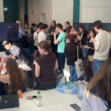 Photo of students gathering and chatting with pizza in classroom