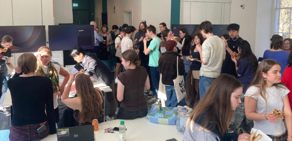 Photo of students gathering and chatting with pizza in classroom