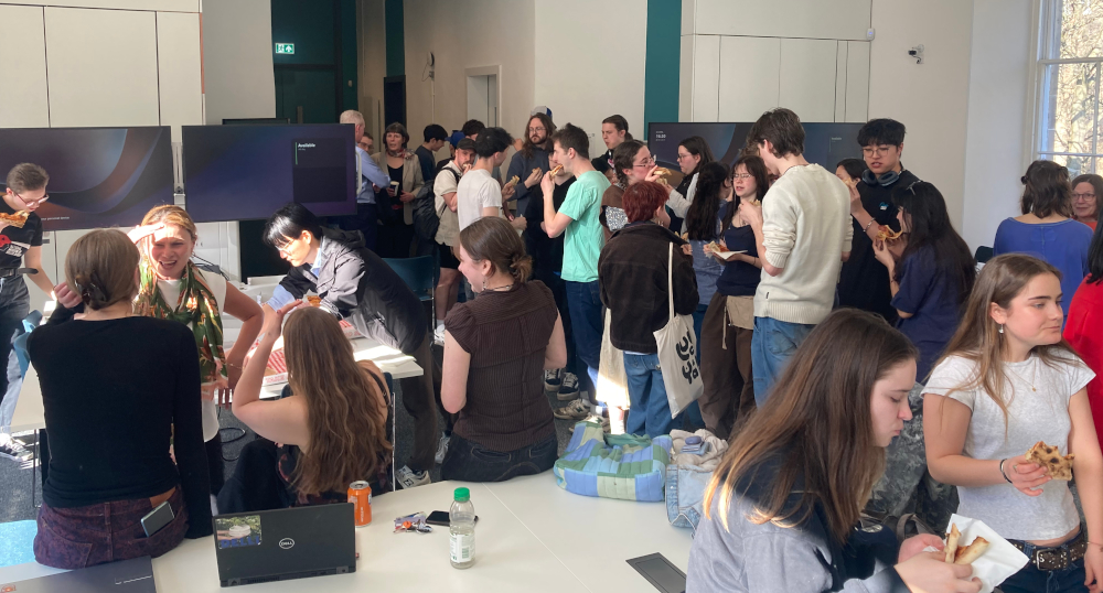Photo of students gathering and chatting with pizza in classroom