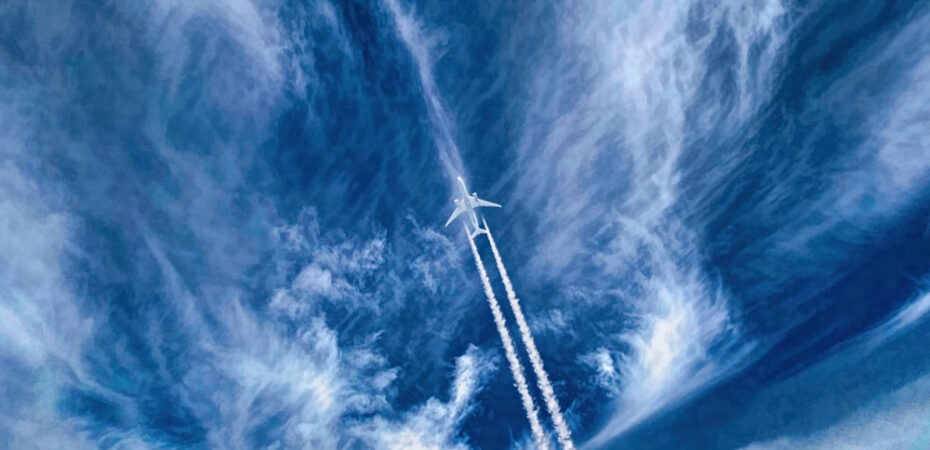 Photo of a plane in sky with trails and clouds