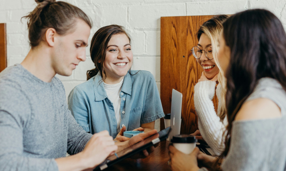 Group of students laughing and chatting around a table