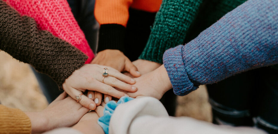 7 hands coming together in middle of circle