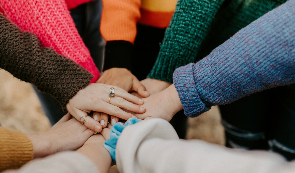 7 hands coming together in middle of circle