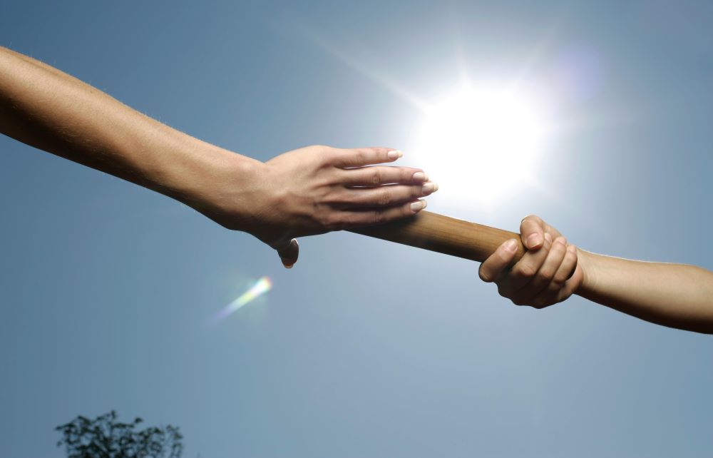 Two hands passing a baton between them