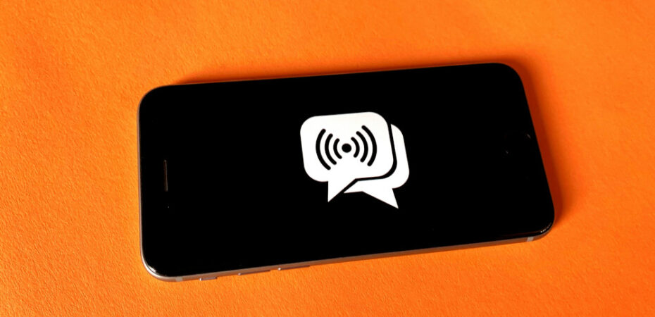 Mobile phone with chat emoji lying on orange square