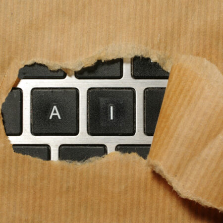 Keyboard under brown paper being ripped to reveal keys A and I