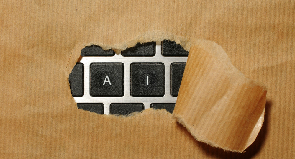 Keyboard under brown paper being ripped to reveal keys A and I