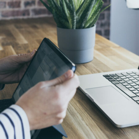 Person sitting in front of a tablet and laptop
