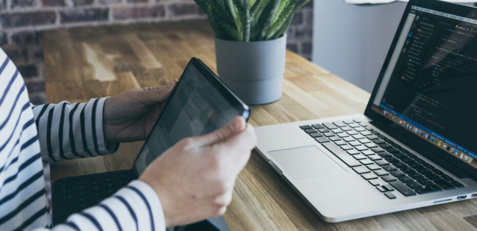 Person sitting in front of a tablet and laptop