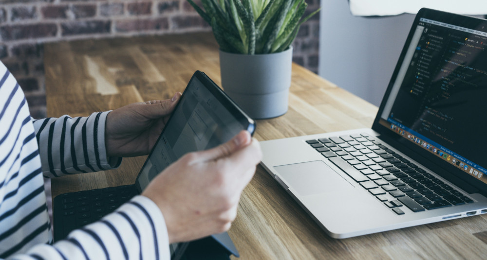 Photo of person holding tablet in front of laptop