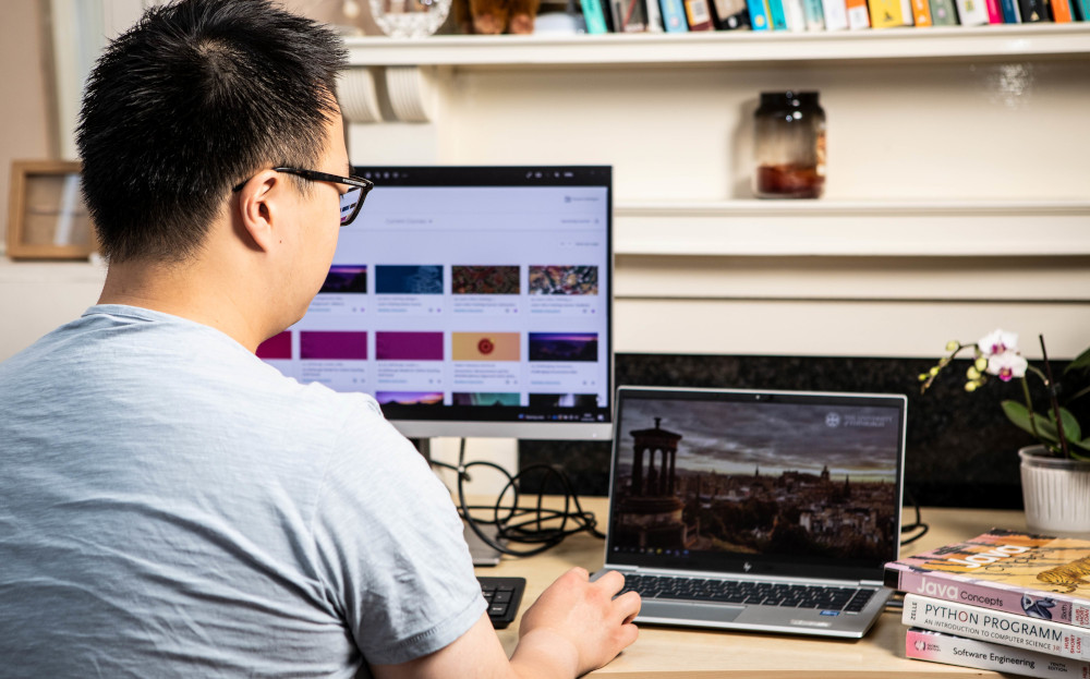 Student as desk with laptop and desktop