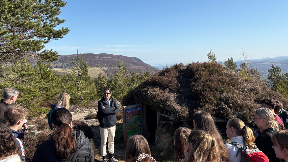 Students listening to a talk on top of a Scottish mountain in a community forest in Scotland.