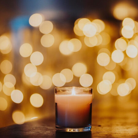 Image of candle in focus, and fairy lights blurred in background