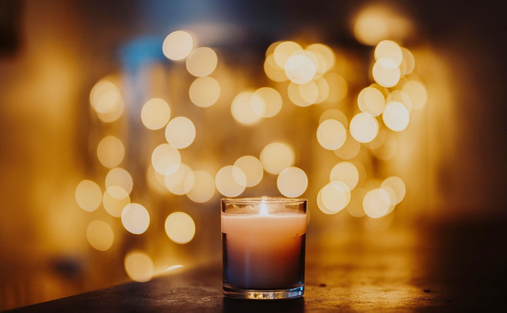 Image of candle in focus, and fairy lights blurred in background