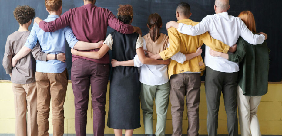 Student and staff linking arms facing blackboard