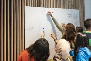 Students drawing on a white board