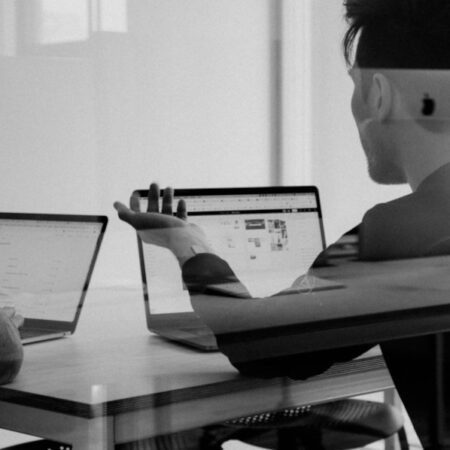 people talking in front of open laptops