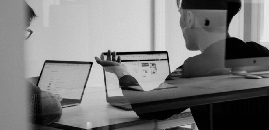 people talking in front of open laptops