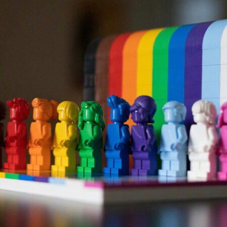 Photo of lego figures in rainbow colours standing on a rainbow platform.