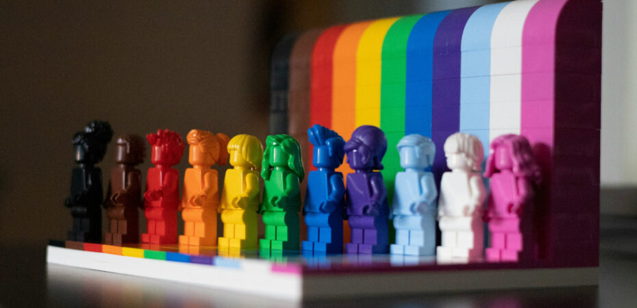 Photo of lego figures in rainbow colours standing on a rainbow platform.