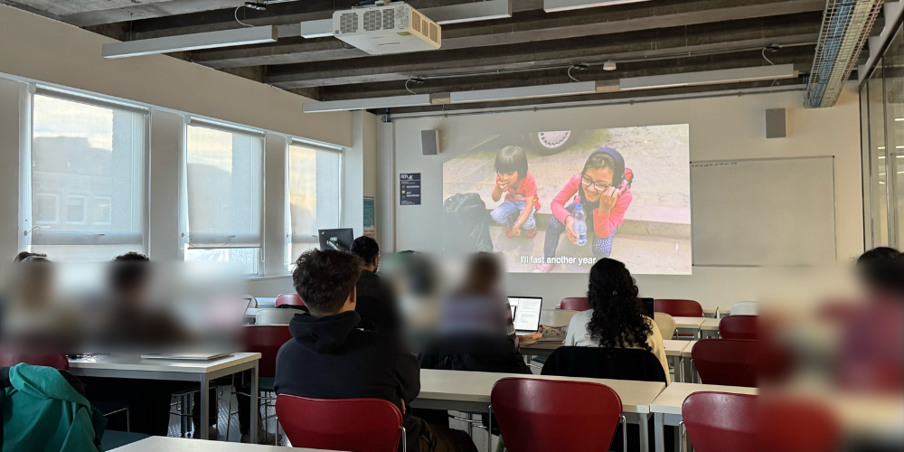 Photo of classroom watching Screening of Midnight Traveller film on projector. 