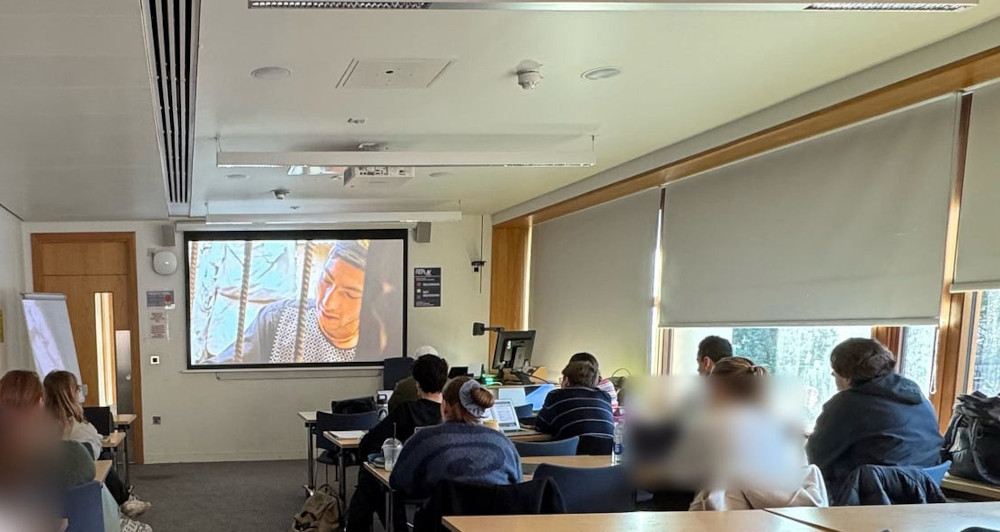 Students in classroom watching Screening of Three Songs for BeNazeer film on projector.