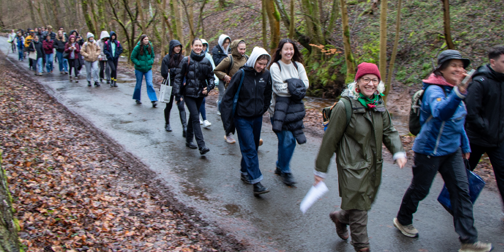 Students walking along woodland path in rain