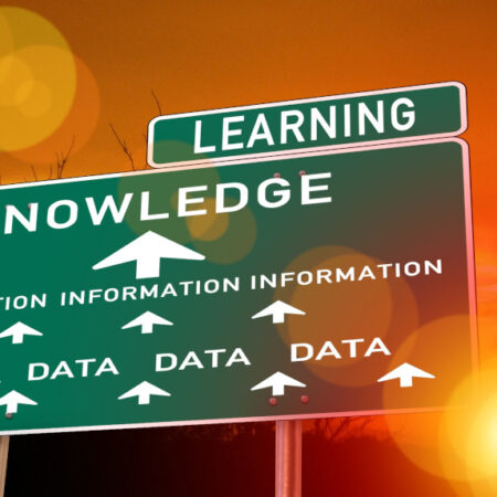 Image of a road sign with 'data' and arrow to word 'information' then arrow to word 'knowledge', and then the word 'learning' - with sunset behind.