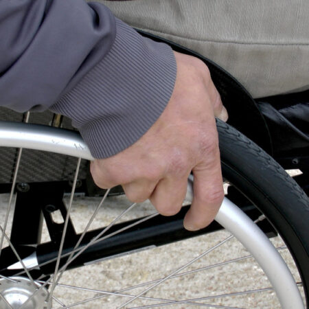 Photo of man in wheelchair zoomed in with his hand on wheel