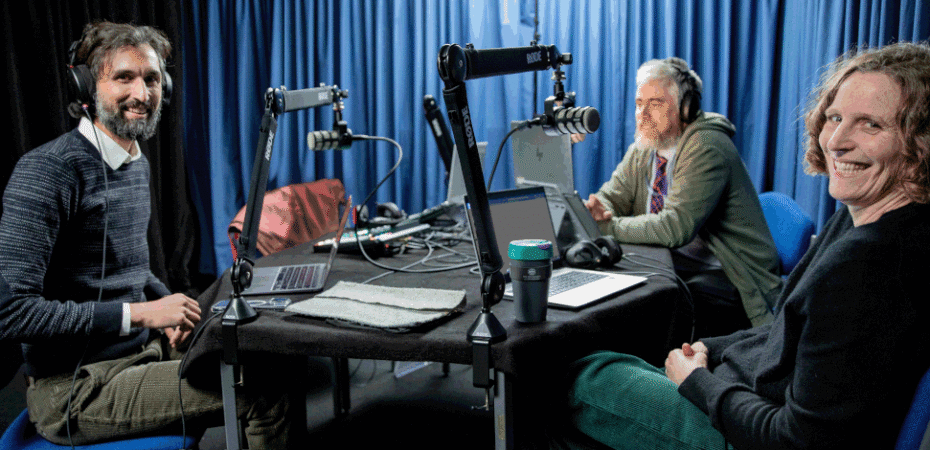 Photo of 3 colleagues sitting around podcast table in podcast studio.