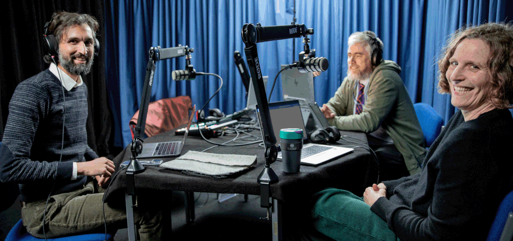 Photo of 3 colleagues sitting around podcast table in podcast studio.