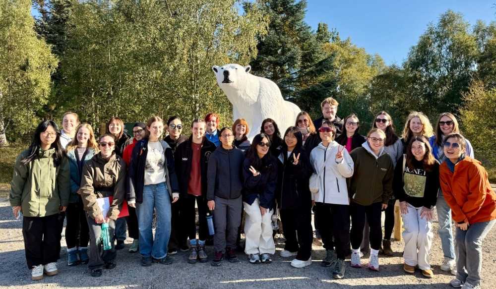 Students gathered in front of a statue of a polar bear