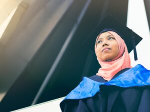 A photo of a hijabi woman with graduation cap looking into the distance